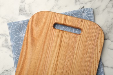 Photo of Wooden cutting board and napkin on white marble table, top view. Space for text