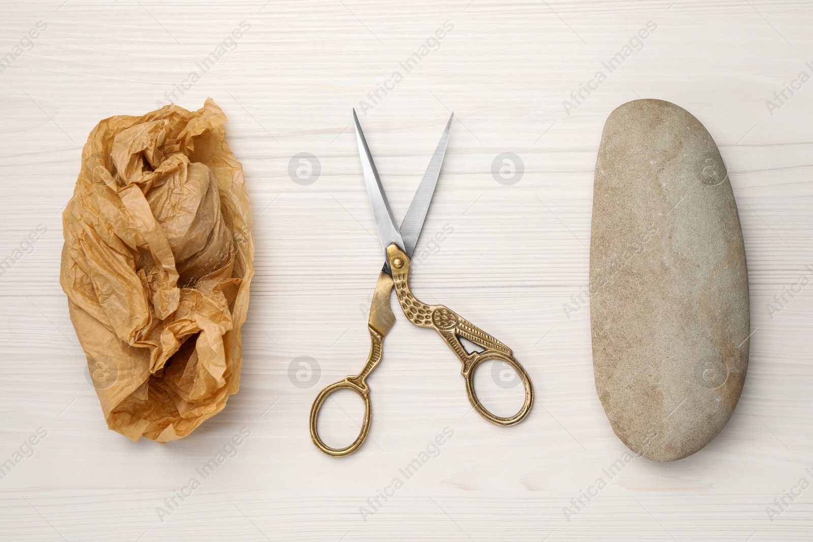 Photo of Rock, crumpled paper and scissors on wooden background, flat lay