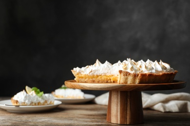 Stand with delicious lemon meringue pie on wooden table, space for text