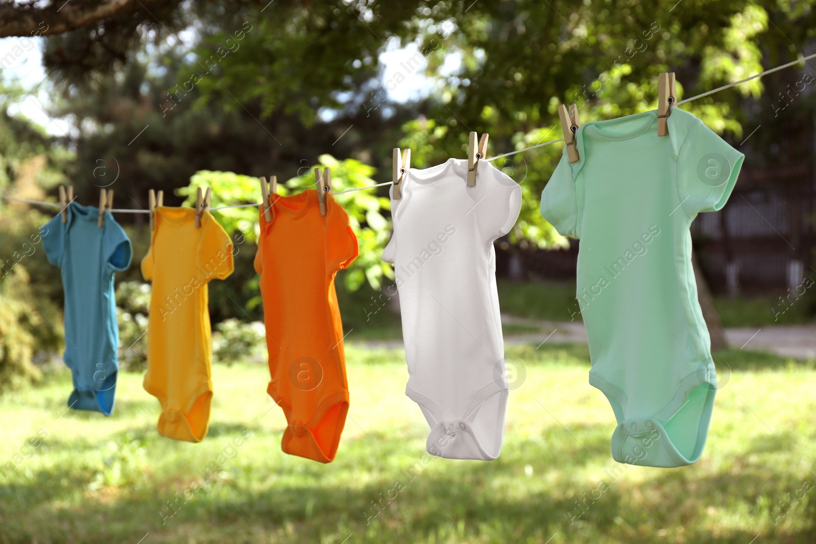 Photo of Colorful baby onesies hanging on clothes line outside