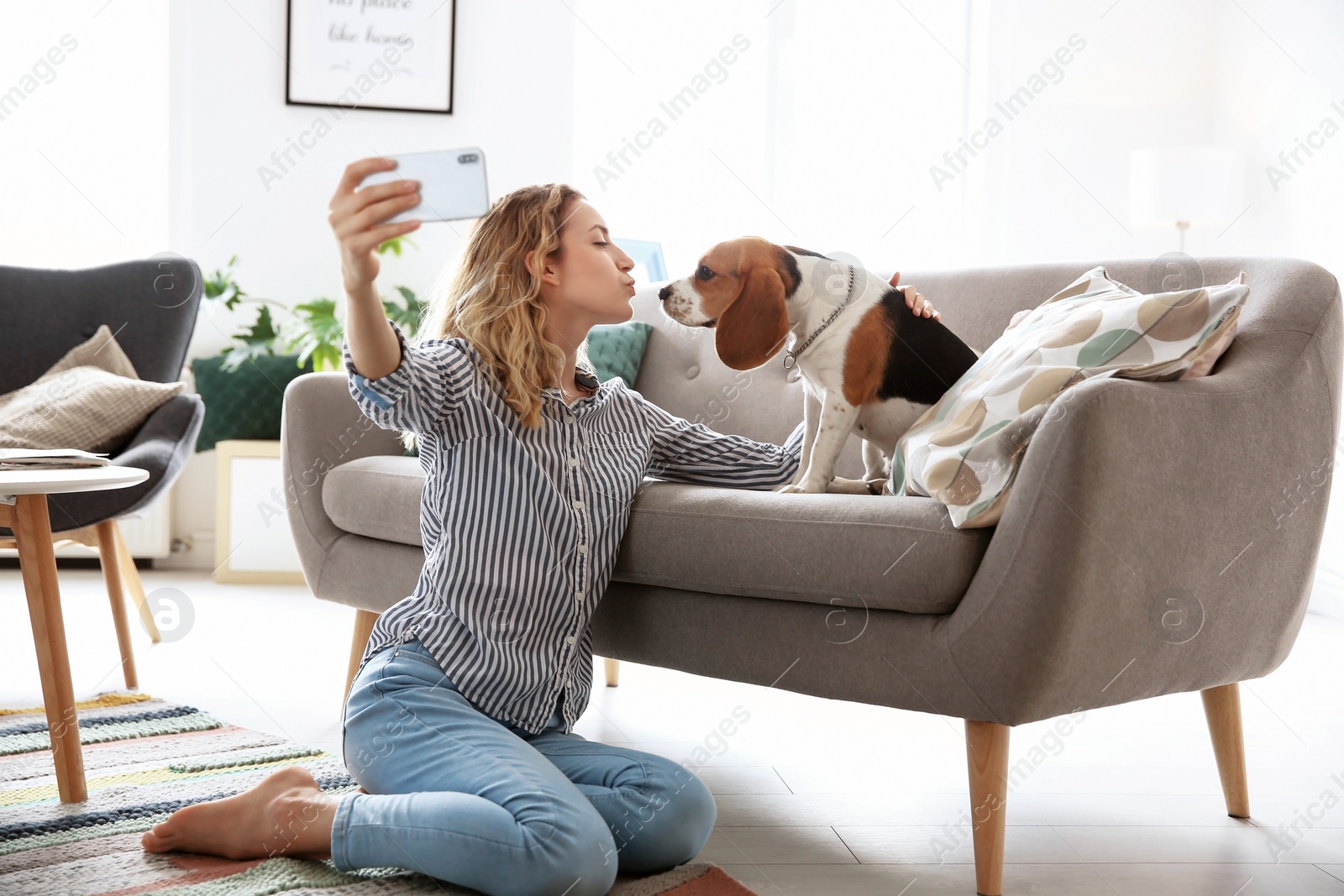 Photo of Young woman taking selfie with her dog at home