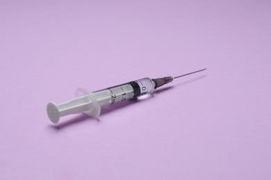 Disposable syringe with needle and medicine on violet background