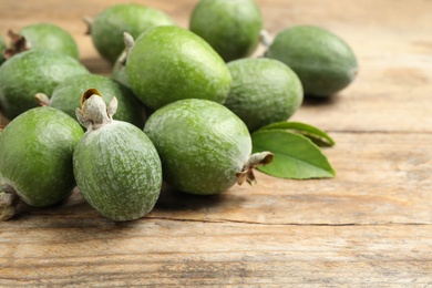 Photo of Fresh green feijoa fruits on wooden table, closeup. Space for text