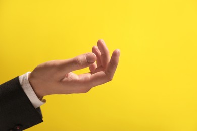 Photo of Man holding something in hand on yellow background, closeup. Space for text