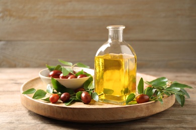 Photo of Glass bottle with jojoba oil and seeds on wooden table