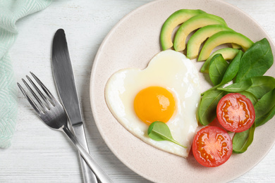 Tasty breakfast with heart shaped fried egg served on white wooden table, flat lay