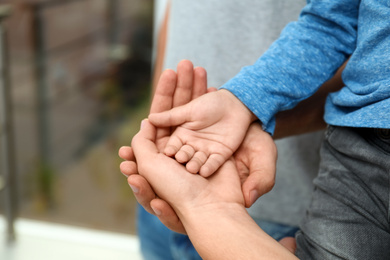 Photo of Happy family holding hands indoors, closeup view