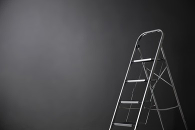 Photo of Modern metal stepladder against grey background. Space for text