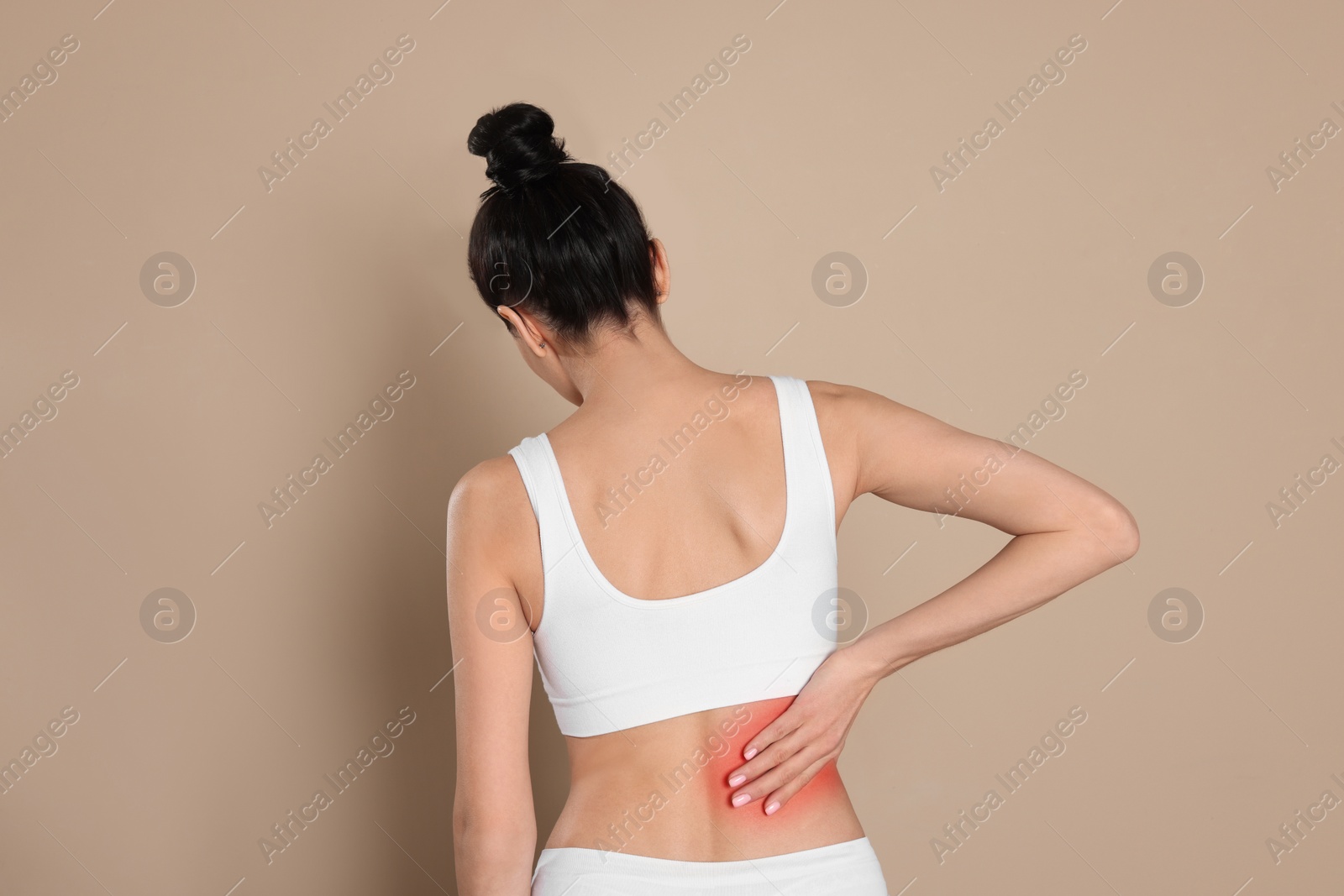 Image of Woman suffering from pain in back on beige background