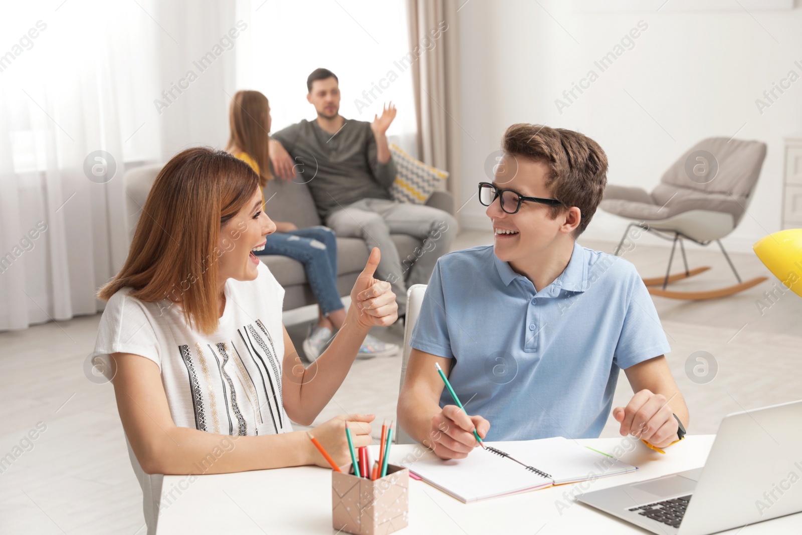 Photo of Mother helping her teenager son with homework indoors