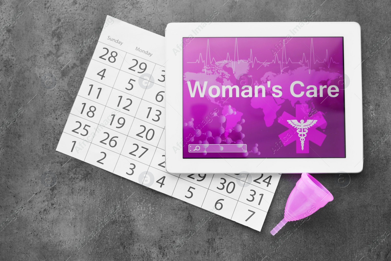 Photo of Flat lay composition with tablet, menstrual cup and calendar on grey background. Gynecological care