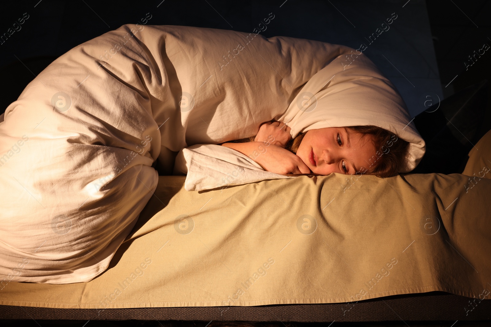 Photo of Little girl hiding from monster in duvet at night