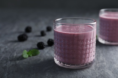 Photo of Glass with blackberry yogurt smoothie on grey table