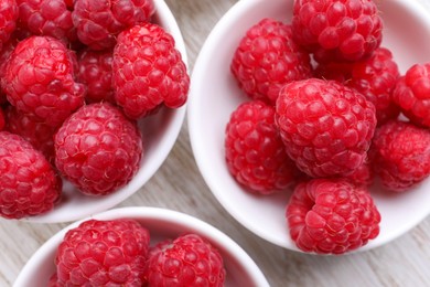 Photo of Tasty ripe raspberries on white wooden table, flat lay
