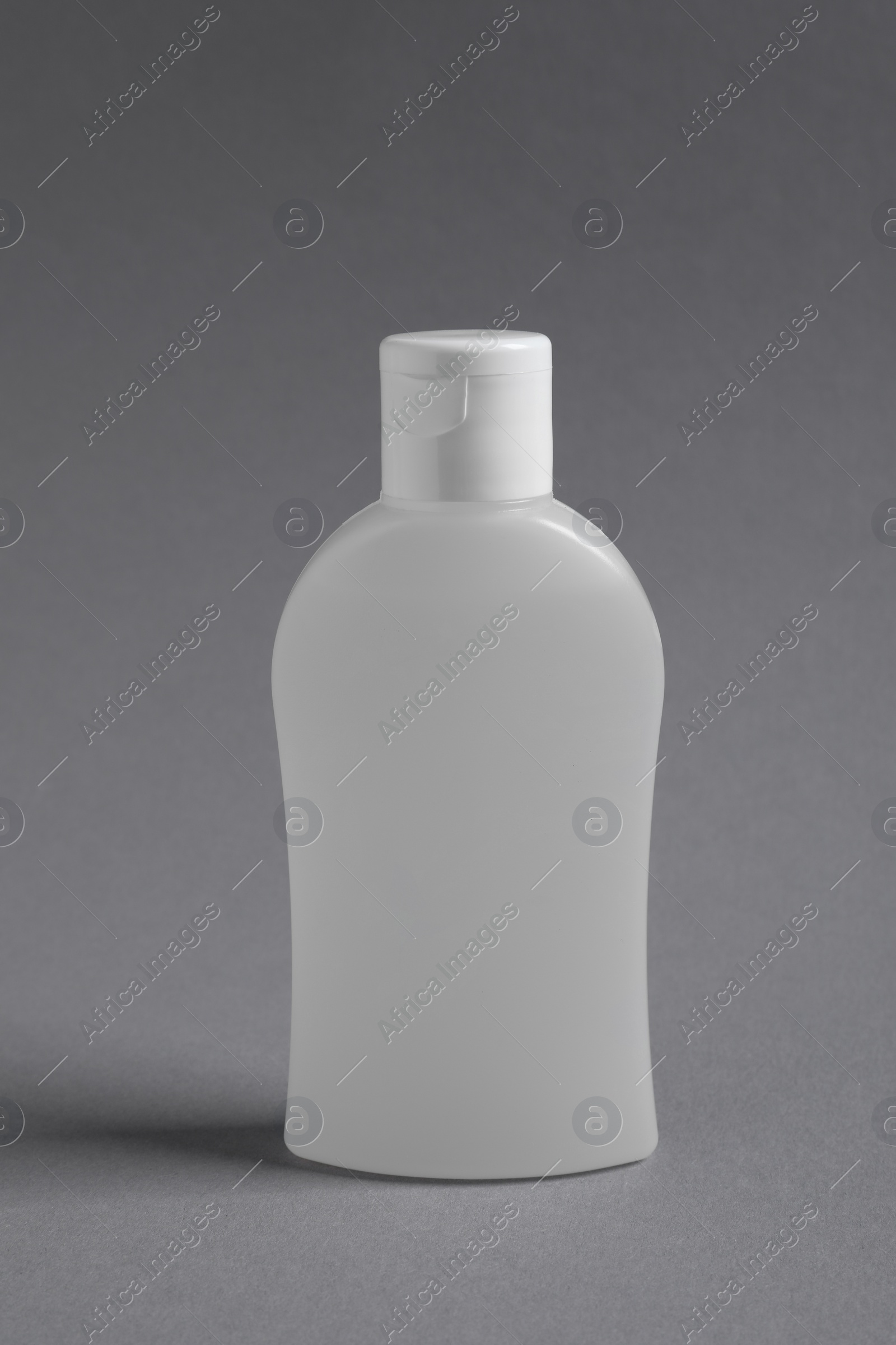 Photo of Bottle with cosmetic product on grey background