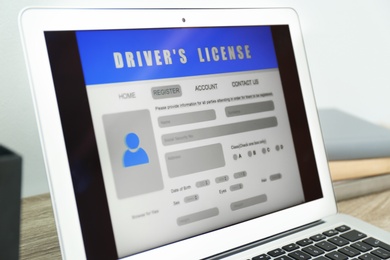 Photo of Laptop with driver's license application form on table, closeup