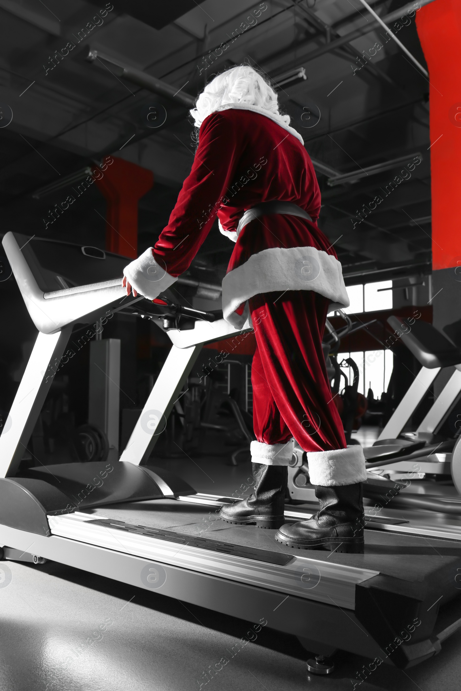 Photo of Authentic Santa Claus training on treadmill in modern gym