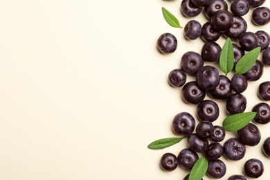 Photo of Fresh acai berries with leaves on beige background, flat lay. Space for text