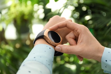 Photo of Mature woman using smart watch outdoors, closeup