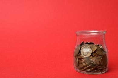 Photo of Glass jar with coins on red background, space for text