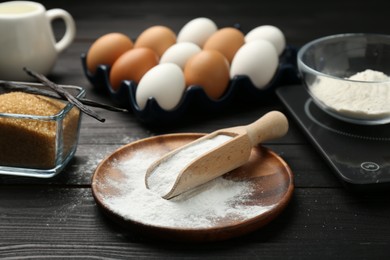 Photo of Baking powder and other products on black wooden table, closeup