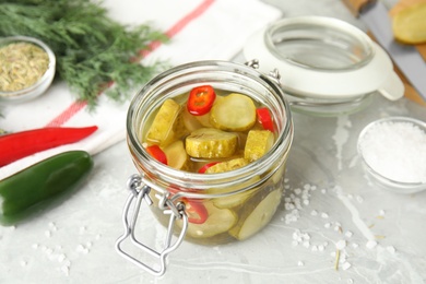 Photo of Jar with pickled cucumbers on grey table
