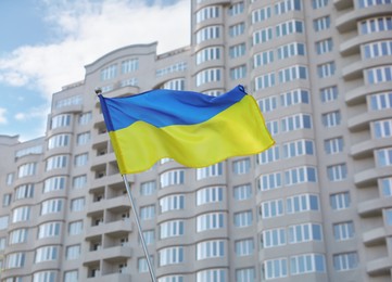 Photo of National flag of Ukraine fluttering near building on sunny day