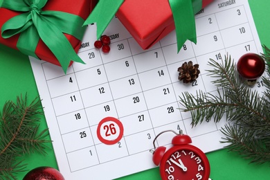 Photo of Flat lay composition with calendar and gifts on green background. Boxing day concept