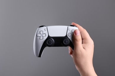 Photo of Woman using wireless game controller on grey background, closeup