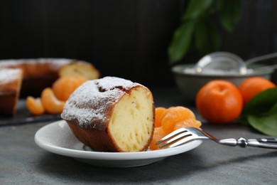 Photo of Piece of delicious homemade yogurt cake with powdered sugar and tangerines on gray table