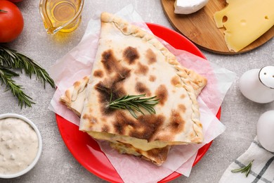 Photo of Tasty pizza calzones with cheese and different products on light grey table, flat lay