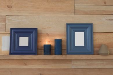 Photo of Shelf with burning candles against wooden wall