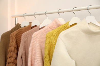 Photo of Rack with stylish warm clothes indoors, closeup