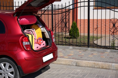 Photo of Family car with open trunk full of luggage in city. Space for text