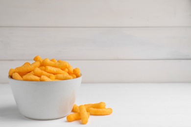 Photo of Bowl with crunchy cheesy corn snack on white table, space for text