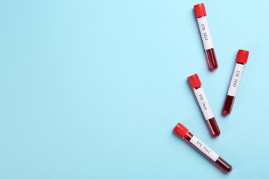 Photo of Tubes with blood samples and labels STD Test on light blue background, flat lay. Space for text