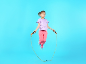 Photo of Full length portrait of girl jumping rope on color background