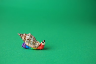 Photo of Snail made from plasticine on green background, space for text. Children's handmade ideas