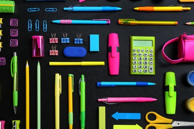 Photo of Different bright school stationery on black background, flat lay