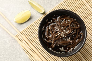 Photo of Tasty buckwheat noodles (soba) with sauce served on light table, flat lay