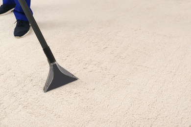 Photo of Man removing dirt from carpet with vacuum cleaner indoors, closeup. Space for text