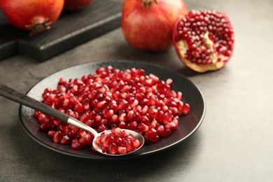 Photo of Ripe juicy pomegranate grains on grey table