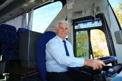 Photo of Professional bus driver at steering wheel. Passenger transportation