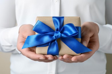 Photo of Woman holding gift box with blue bow, closeup