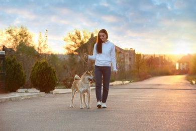 Photo of Young woman walking her adorable Akita Inu dog outdoors