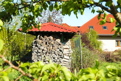 Photo of Shed with stacked firewood outdoors on sunny day