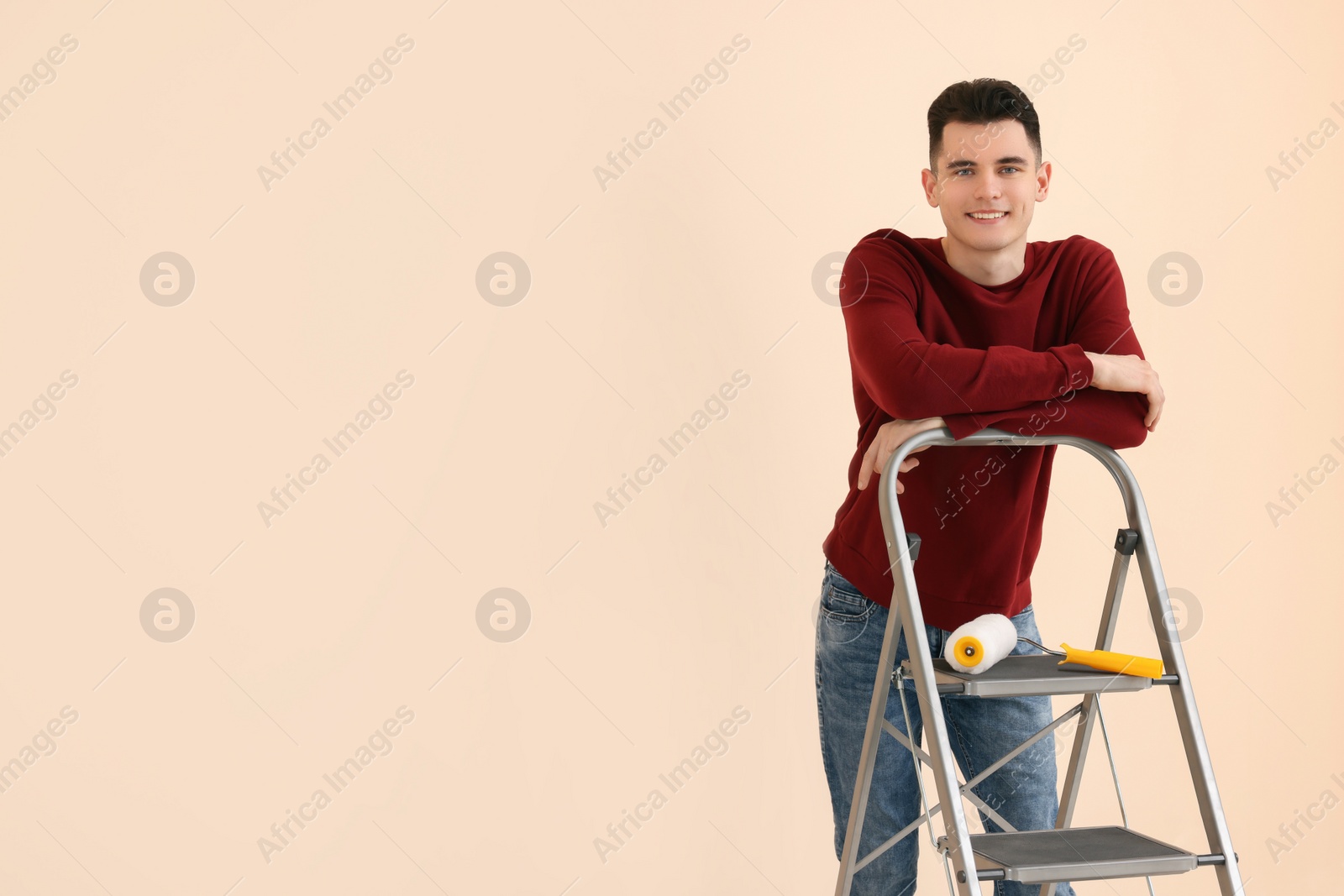 Photo of Young handsome man near metal stepladder indoors, space for text. Room renovation