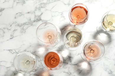 Photo of Different glasses with wine on marble background, flat lay
