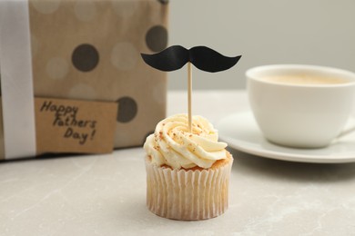 Photo of Delicious cupcake with mustache topper on light table. Father's day celebration