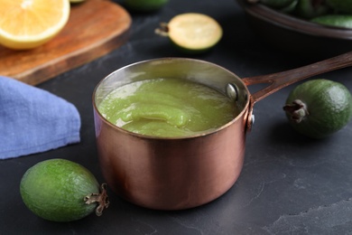 Photo of Feijoa jam and fresh fruits on black table, closeup